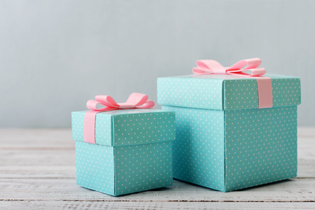 Blue polka dots gift boxes with pink ribbons on wooden backgroundの写真素材