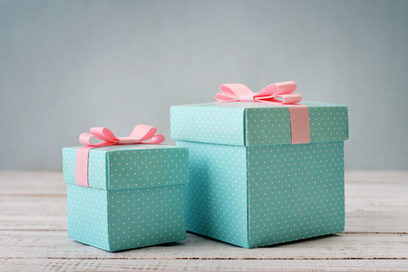 Blue polka dots gift boxes with pink ribbons on wooden backgroundの写真素材