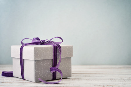 Gift box with violet ribbon on blue backgroundの写真素材