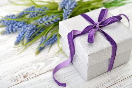 Gift box with violet ribbon and bouquet of hyacinth on wooden backgroundの写真素材
