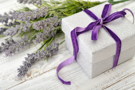 Gift box with violet ribbon and bouquet of lavender on wooden backgroundの写真素材