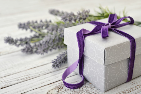Gift box with violet ribbon and bouquet of lavender on wooden backgroundの写真素材