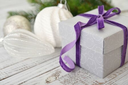 Gift box with violet ribbon and christmas decor on wooden backgroundの写真素材