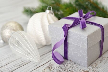 Gift box with violet ribbon and christmas decor on wooden backgroundの写真素材