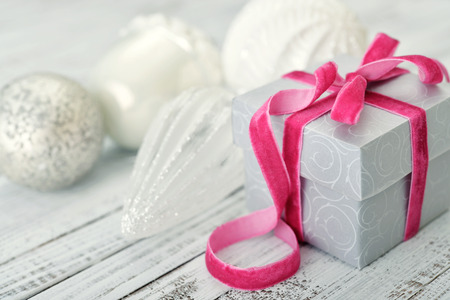 Gift box with pink ribbon and christmas decor on wooden backgroundの写真素材