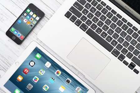 KIEV, UKRAINE - JANUARY 29, 2015: Apple iPhone 5s, iPad Air 2 and MacBook Air Early 2014 on the table closeup. Apple Inc. is an American multinational corporation that designs, develops, and sells consumer electronics.のeditorial素材