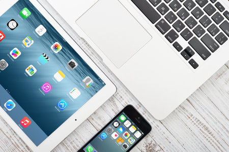 KIEV, UKRAINE - JANUARY 29, 2015: Apple iPhone 5s, iPad Air 2 and MacBook Air on table. Apple Inc. is an American multinational corporation that designs, develops, and sells consumer electronics.のeditorial素材