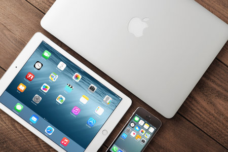 KIEV, UKRAINE - JANUARY 29, 2015: Apple iPhone 5s, iPad Air 2 and MacBook Air on table. Apple Inc. is an American multinational corporation that designs, develops, and sells consumer electronics.のeditorial素材