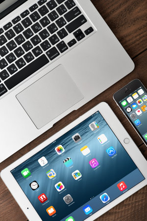 KIEV, UKRAINE - JANUARY 29, 2015: Apple iPhone 5s, iPad Air 2 and MacBook Air on table. Apple Inc. is an American multinational corporation that designs, develops, and sells consumer electronics.のeditorial素材