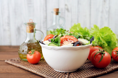 Salad mix with lettuce, tomato, cucumber and quail eggs in bowl on wooden backgroundの写真素材