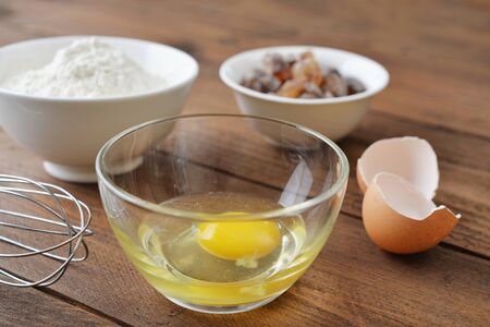 Raw egg and ingredients for baking on a wooden backgroundの写真素材
