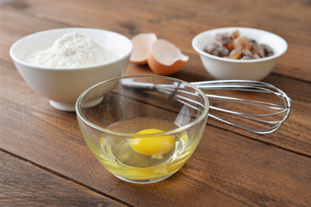 Raw egg and ingredients for baking on a wooden backgroundの写真素材