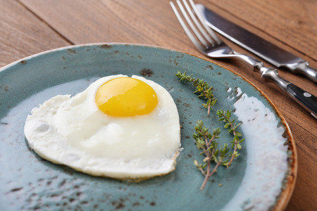 Fried egg in shape of heart on blue plate closeupの写真素材