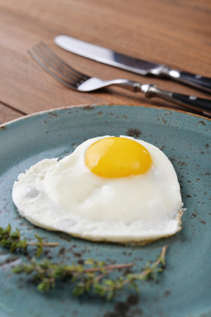 Fried egg in shape of heart on blue plate closeupの写真素材