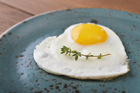 Fried egg in shape of heart on blue plate closeupの写真素材