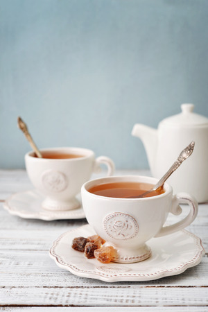 Cup of tea and sugar with teapot over blue backgroundの写真素材