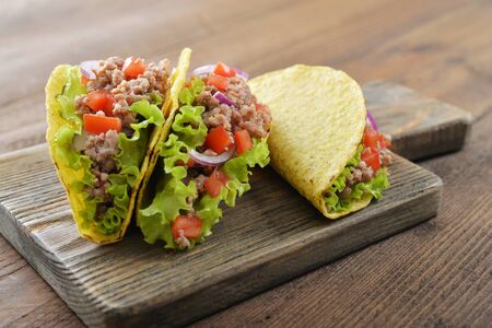 Mexican tacos with meat, onion and tomato on wooden backgroundの写真素材