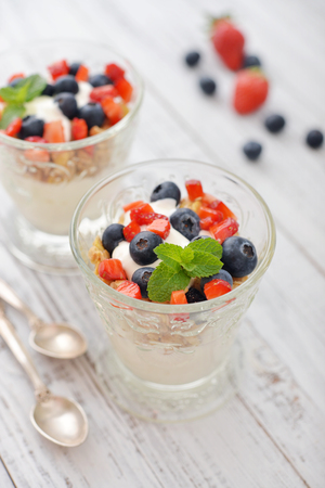 Granola with yogurt and blueberry and strawberry in glass on wooden bakgroundの写真素材