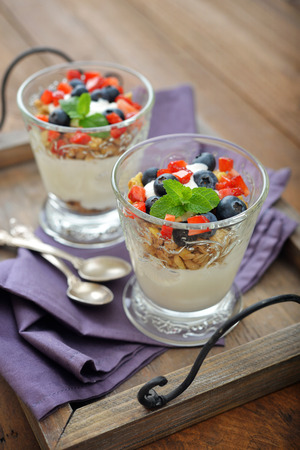 Granola with yogurt and blueberry and strawberry in glass on wooden tray closeupの写真素材