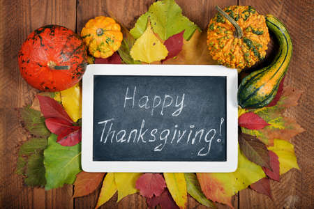 Chalkboard over wooden background with autumn leaves and decorative pumpkins, top viewの写真素材