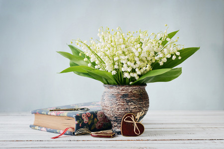Bouquet of may-lily with book  and ceramic heart on blue backgroundの写真素材