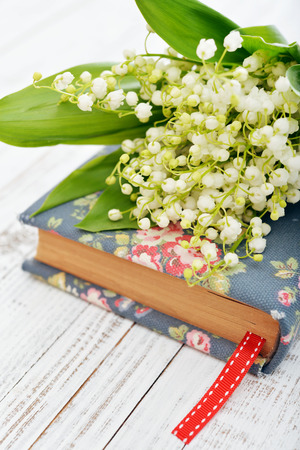 Bouquet of may-lily with book closeup  on wooden backgroundの写真素材