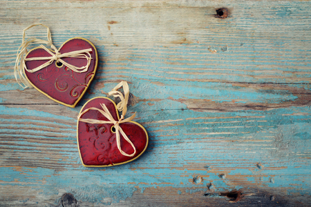 Two handmade ceramic hearts with bows on wooden backgroundの写真素材