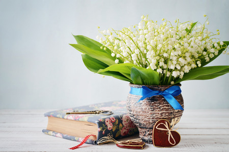 Bouquet of may-lily with book  and ceramic heart on blue backgroundの写真素材
