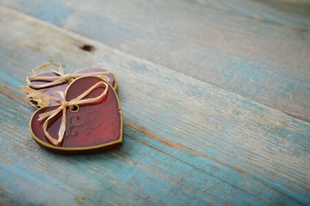 Two handmade ceramic hearts with bows on wooden backgroundの写真素材