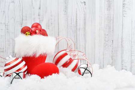 Red Santa's boots with christmas decorations on white wooden backgroundの写真素材