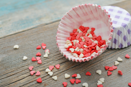 Color candy hearts with cupcake cases on wooden backgroundの写真素材