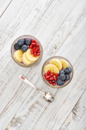 Pudding with chia seeds, yogurt and fresh fruits in glass jars top viewの写真素材