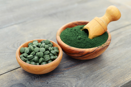 Ground spirulina and spirulina in pills over black wooden backgroundの写真素材