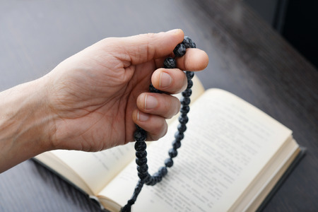 Male hand holding rosary beads closeup and koran on background.の写真素材