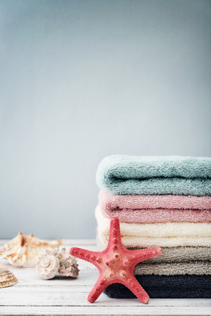 Stack of towels with shells on light blue backgroundの写真素材