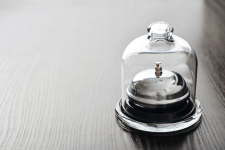 Service bell in glass mini dome on wooden backgroundの写真素材