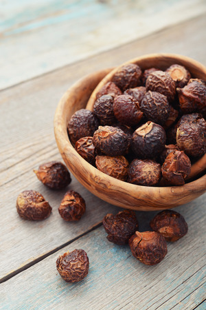 Soap nuts in bowl on wooden background closeupの写真素材