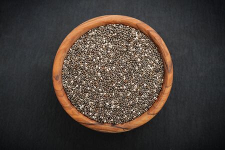 Chia seeds in wooden bowl on slate background, top viewの写真素材