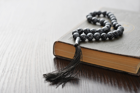 Holy Quran with beads over wooden background closeup. Small shallow DOF.