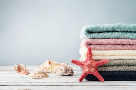 Stack of towels with shells on light blue backgroundの写真素材