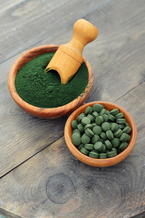 Ground spirulina and spirulina in pills over black wooden backgroundの写真素材