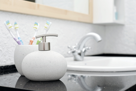 Soap dispenser with a toothbrushes in glass in a bathroom closeupの写真素材