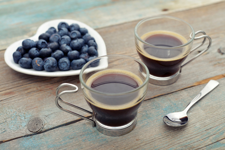 Two glass cups of coffee with berry on wooden backgroundの写真素材