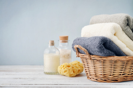 Bath towels of different colors in wicker basket on light backgroundの写真素材