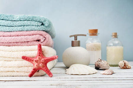 Towels  with bottles of shampoo and sea salt on light backgroundの写真素材