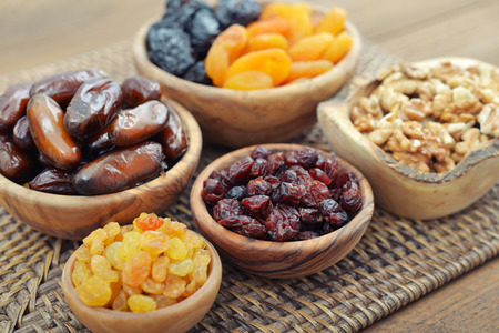 Mix of dried fruits and nuts in wooden bowls closeupの写真素材