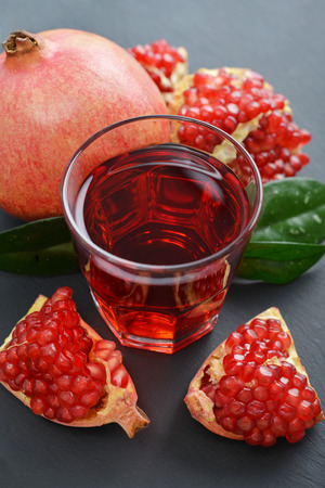 Pomegranate juice in glass and fresh fruits  on slate backgroundの写真素材