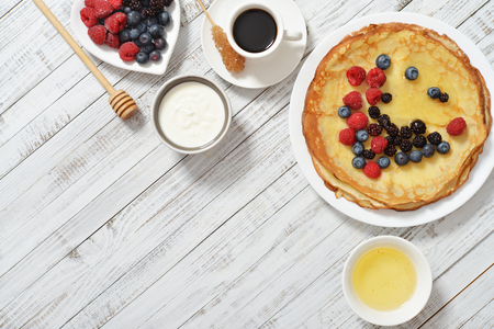 Pancakes with fresh berries and honey on wooden backgroundの写真素材