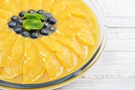Pie with orange slices and blueberry in jelly on wooden background closeupの写真素材