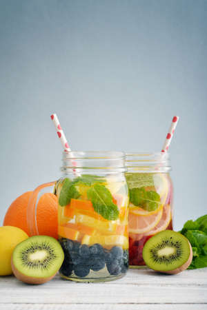 Detox drinks with fresh fruits and berries in glass jars on wooden backgroundの写真素材
